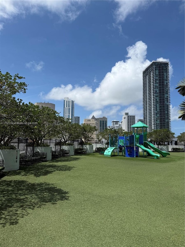 community jungle gym featuring a city view and fence
