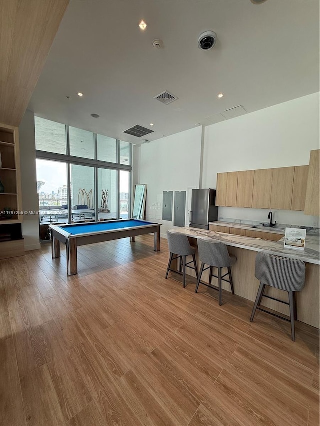 rec room with expansive windows, pool table, light wood-style flooring, electric panel, and a sink