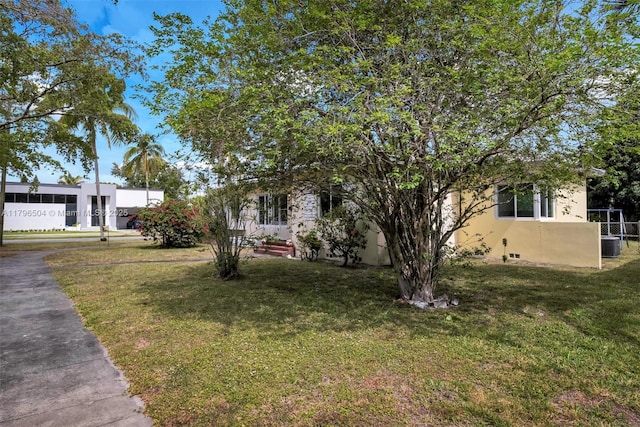 view of front facade with central air condition unit, stucco siding, and a front yard