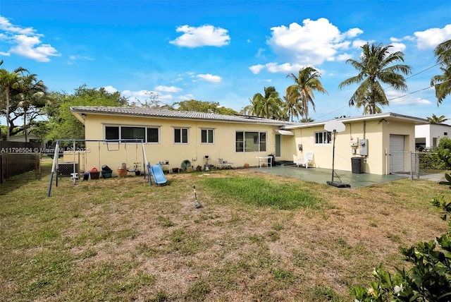 rear view of property with a gate, stucco siding, and a yard
