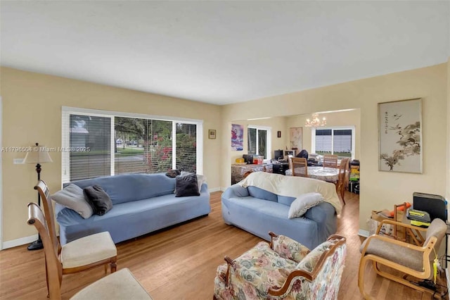 living area with light wood-style flooring, baseboards, and a notable chandelier