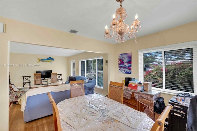 dining space with visible vents, a notable chandelier, plenty of natural light, and wood finished floors