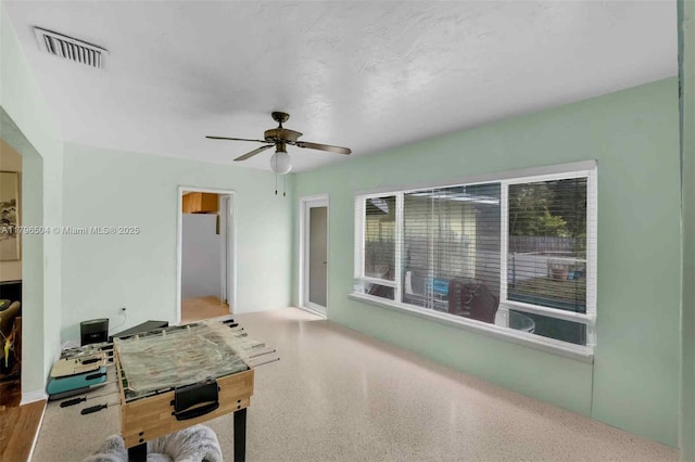 rec room with a ceiling fan, visible vents, and speckled floor