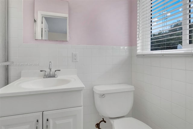 bathroom with toilet, tile walls, and vanity