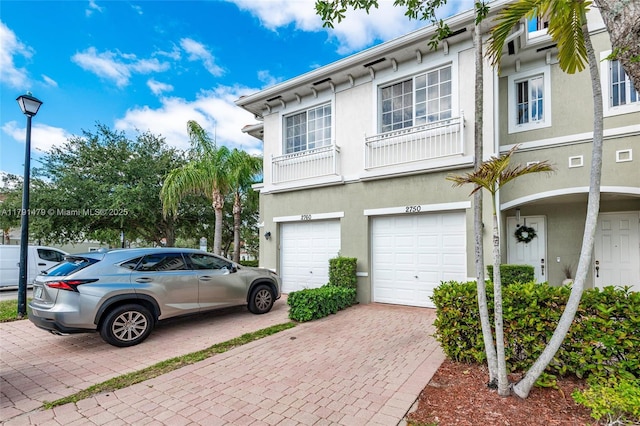 view of side of property featuring an attached garage, stucco siding, and driveway