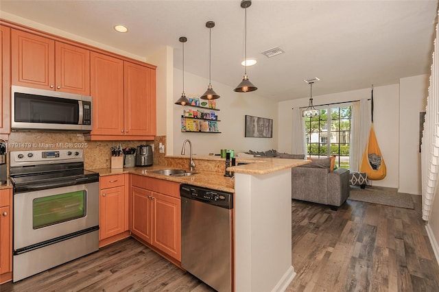 kitchen with visible vents, a sink, a peninsula, wood finished floors, and stainless steel appliances