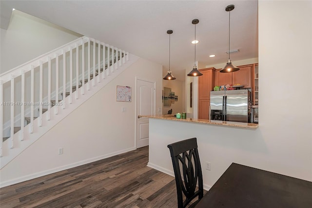 kitchen featuring brown cabinetry, recessed lighting, dark wood-style flooring, stainless steel fridge, and hanging light fixtures