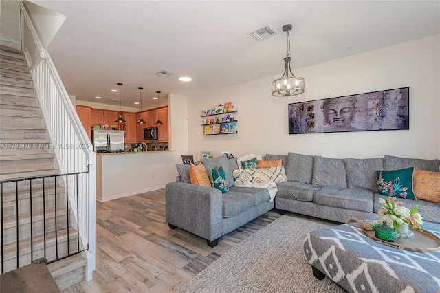 living area featuring stairs, visible vents, recessed lighting, light wood-style flooring, and a notable chandelier