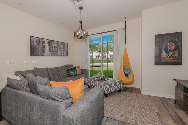 living area with an inviting chandelier, visible vents, wood finished floors, and baseboards