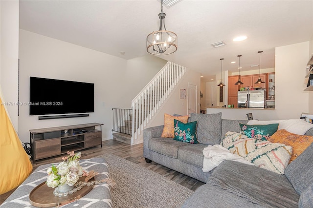 living area featuring recessed lighting, visible vents, a chandelier, wood finished floors, and stairway
