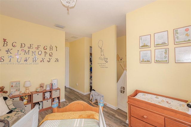 bedroom with visible vents, wood finished floors, and baseboards