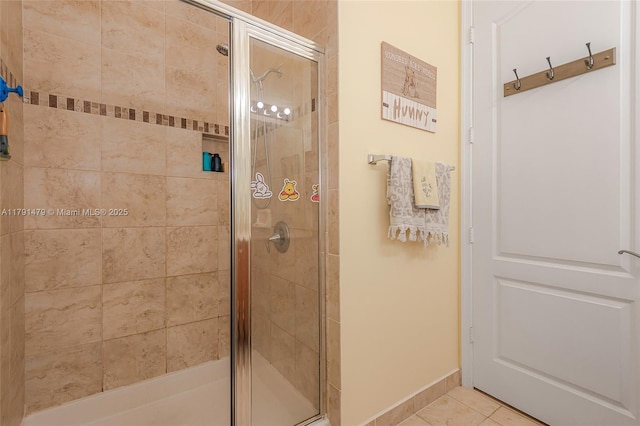 bathroom featuring baseboards, tile patterned flooring, and a stall shower