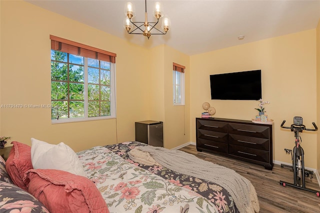 bedroom with wood finished floors, baseboards, and a notable chandelier