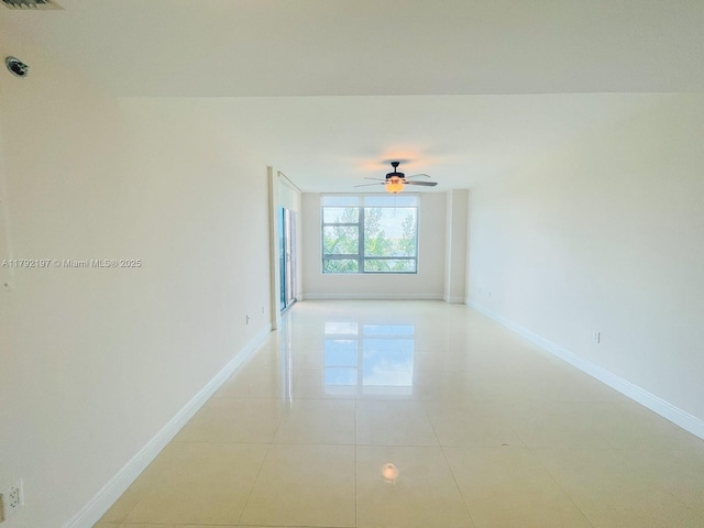 unfurnished room with a ceiling fan, baseboards, and light tile patterned flooring