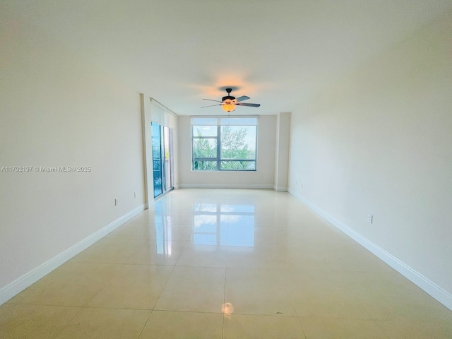 empty room with ceiling fan, baseboards, and light tile patterned floors