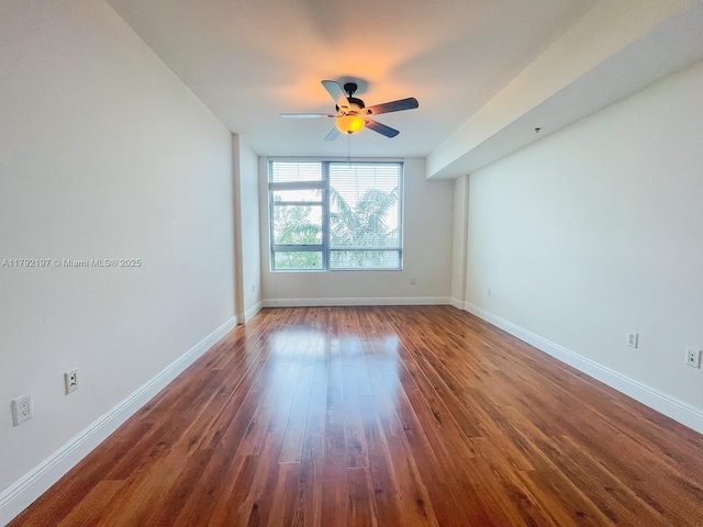 spare room with dark wood-type flooring, baseboards, and ceiling fan