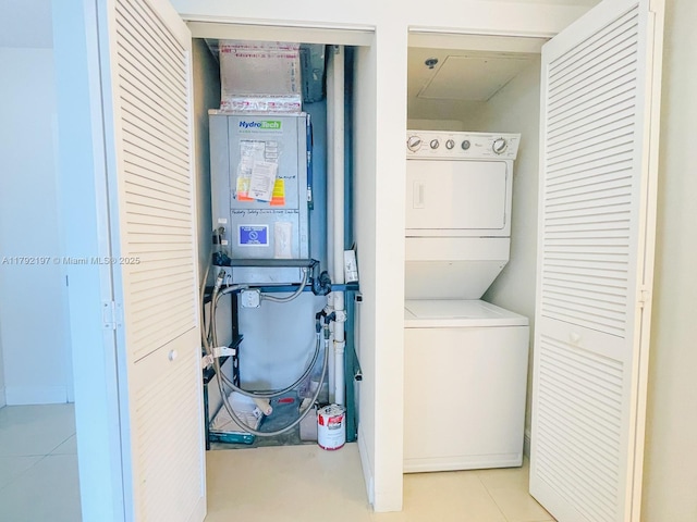 laundry room featuring light tile patterned floors, stacked washer and dryer, and laundry area