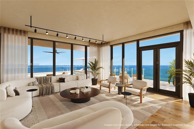 living area featuring rail lighting, a water view, and wood finished floors
