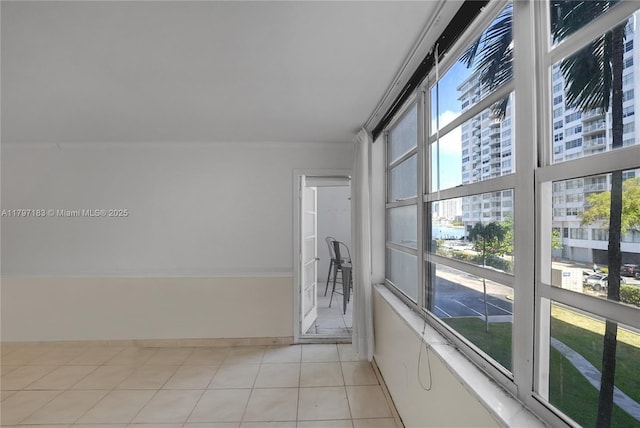 empty room with baseboards, a view of city, and light tile patterned flooring