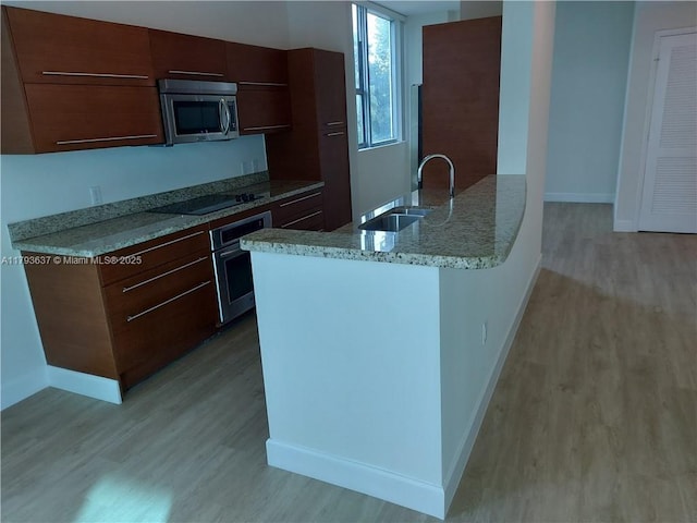 2641 N Flamingo Rd Unit 307N, Sunrise, FL 33323 - kitchen with stainless steel appliances, light wood-style flooring, a sink, baseboards, and light stone countertops