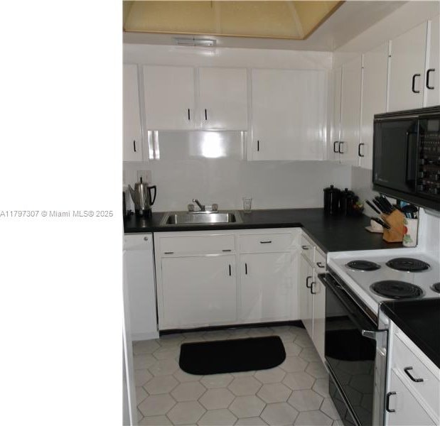 kitchen featuring black microwave, dark countertops, a sink, and electric range