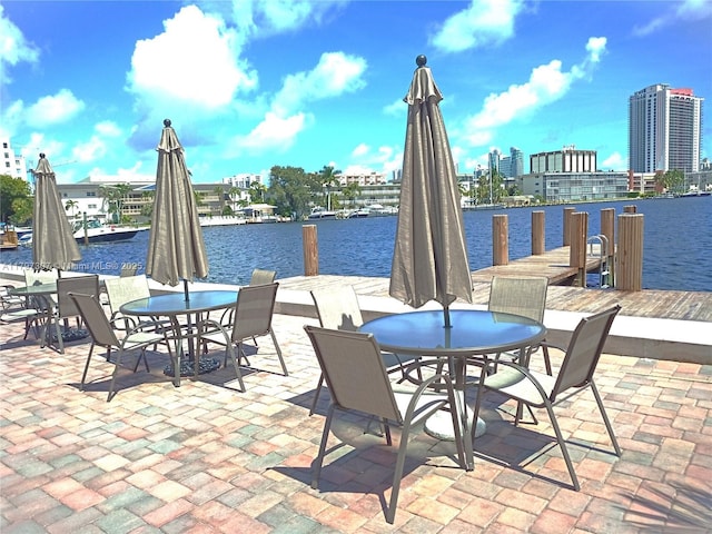 view of patio / terrace featuring a water view, a city view, and outdoor dining area