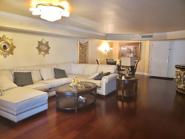 living room with ornamental molding, visible vents, and wood finished floors