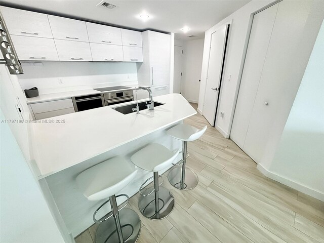 1300 S Miami Ave Unit 2209, Miami, FL 33130 - kitchen featuring a sink, visible vents, recessed lighting, a breakfast bar area, and white cabinets