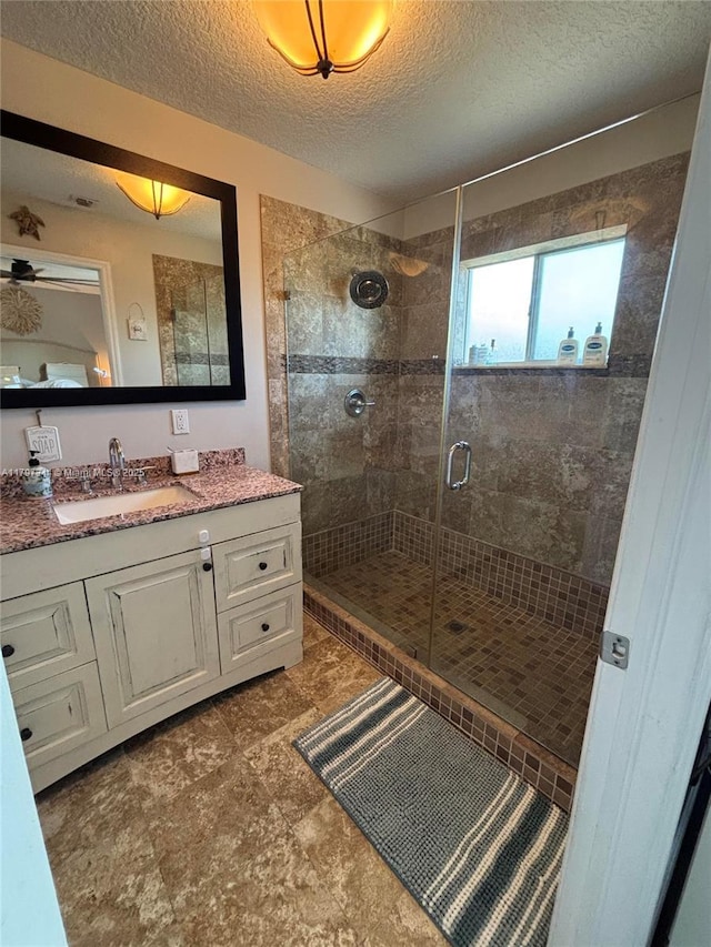 full bath with vanity, a textured ceiling, and a stall shower