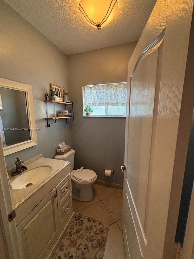 bathroom with toilet, tile patterned flooring, vanity, and a textured ceiling