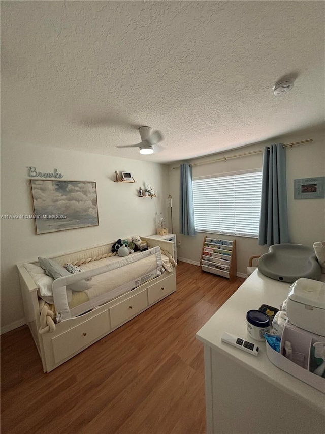 bedroom with a textured ceiling, a ceiling fan, and wood finished floors