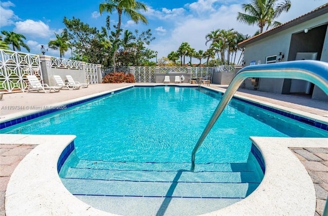 community pool featuring a patio area, a water slide, and fence