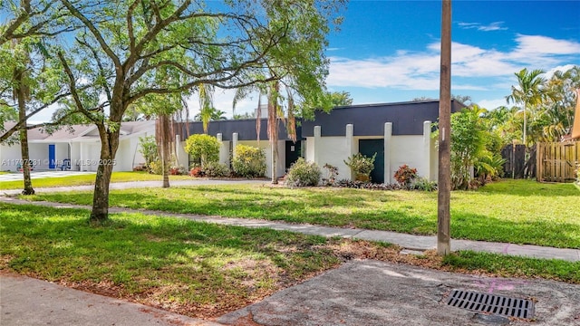 view of front of home with stucco siding, a front lawn, and fence