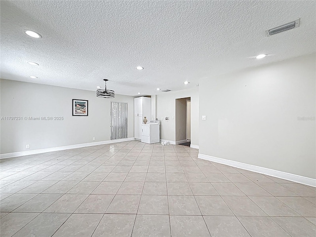 empty room featuring a textured ceiling, baseboards, visible vents, and recessed lighting
