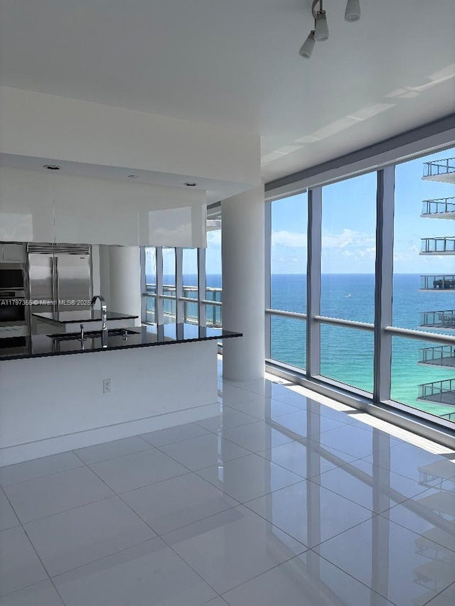 unfurnished room featuring healthy amount of natural light, a water view, and tile patterned flooring