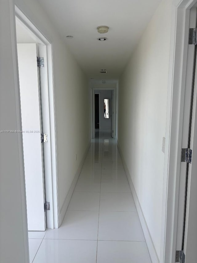 hallway with light tile patterned flooring and baseboards