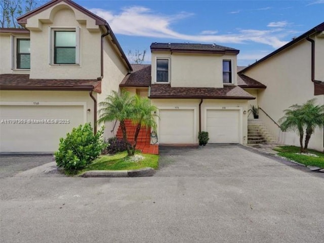 view of property with aphalt driveway, a garage, stucco siding, stairway, and a shingled roof