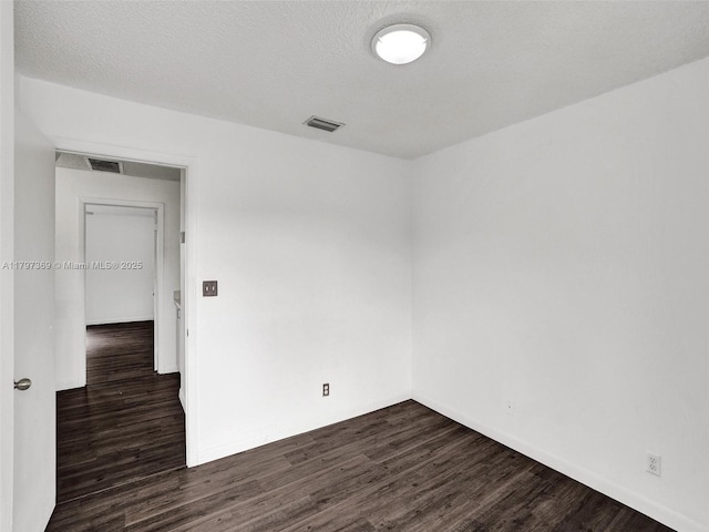 empty room with baseboards, dark wood-style flooring, and visible vents
