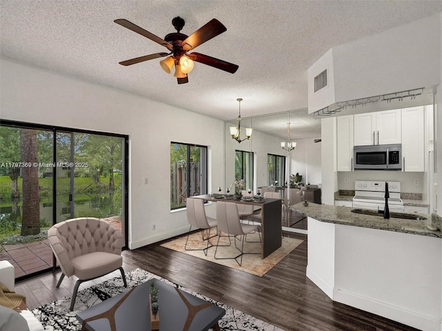 living room with a chandelier, wood finished floors, a textured ceiling, a ceiling fan, and baseboards