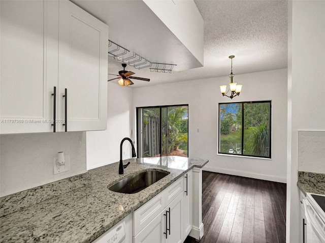 kitchen featuring decorative light fixtures, light stone counters, a sink, ceiling fan with notable chandelier, and white cabinetry