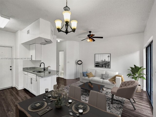 living room with a textured ceiling, dark wood finished floors, a ceiling fan, a chandelier, and baseboards