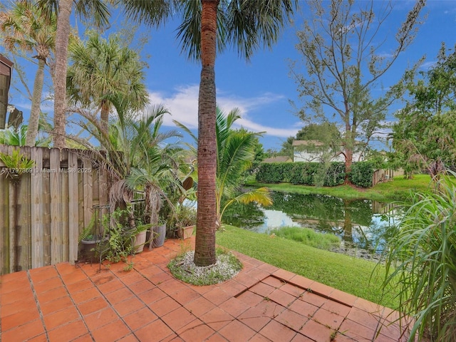 view of patio / terrace featuring a water view and fence