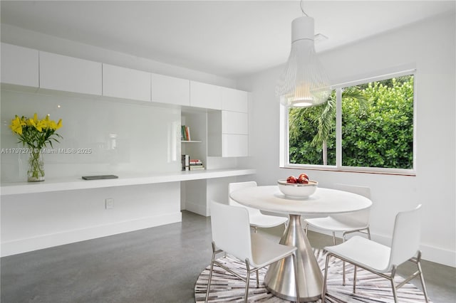 dining area featuring concrete flooring, baseboards, and a healthy amount of sunlight