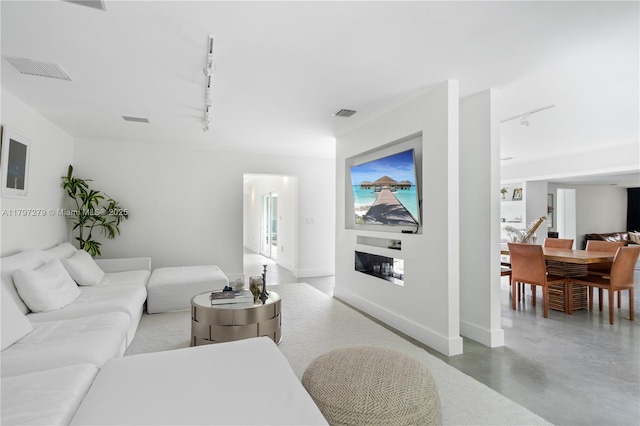 living area featuring rail lighting, baseboards, visible vents, and finished concrete floors