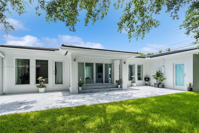 rear view of property with a yard, a patio area, and stucco siding