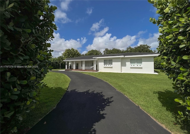 ranch-style home with a front lawn, stucco siding, and driveway