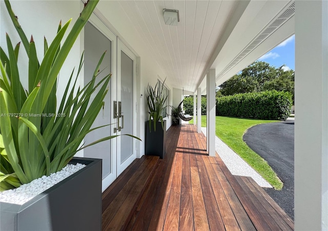 wooden terrace featuring a yard, french doors, and covered porch