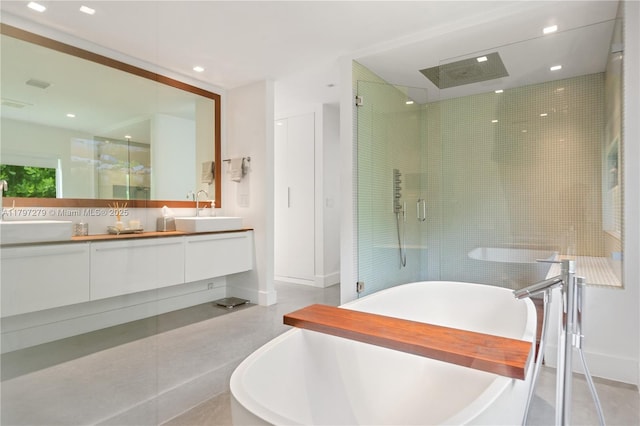 full bath featuring a stall shower, a freestanding tub, a sink, and double vanity