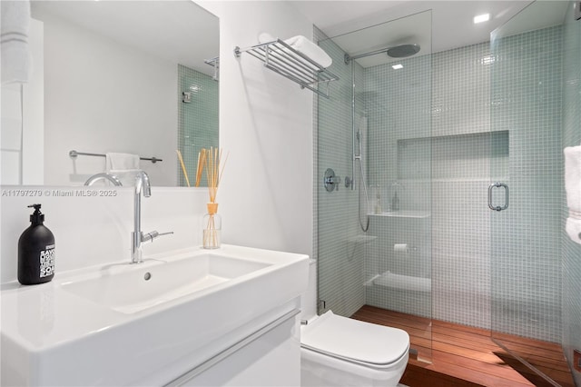 full bath featuring a stall shower, vanity, toilet, and wood finished floors