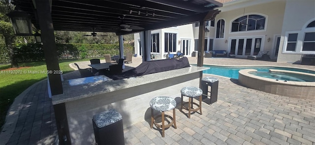 view of pool with a patio area, a pool with connected hot tub, french doors, and a ceiling fan